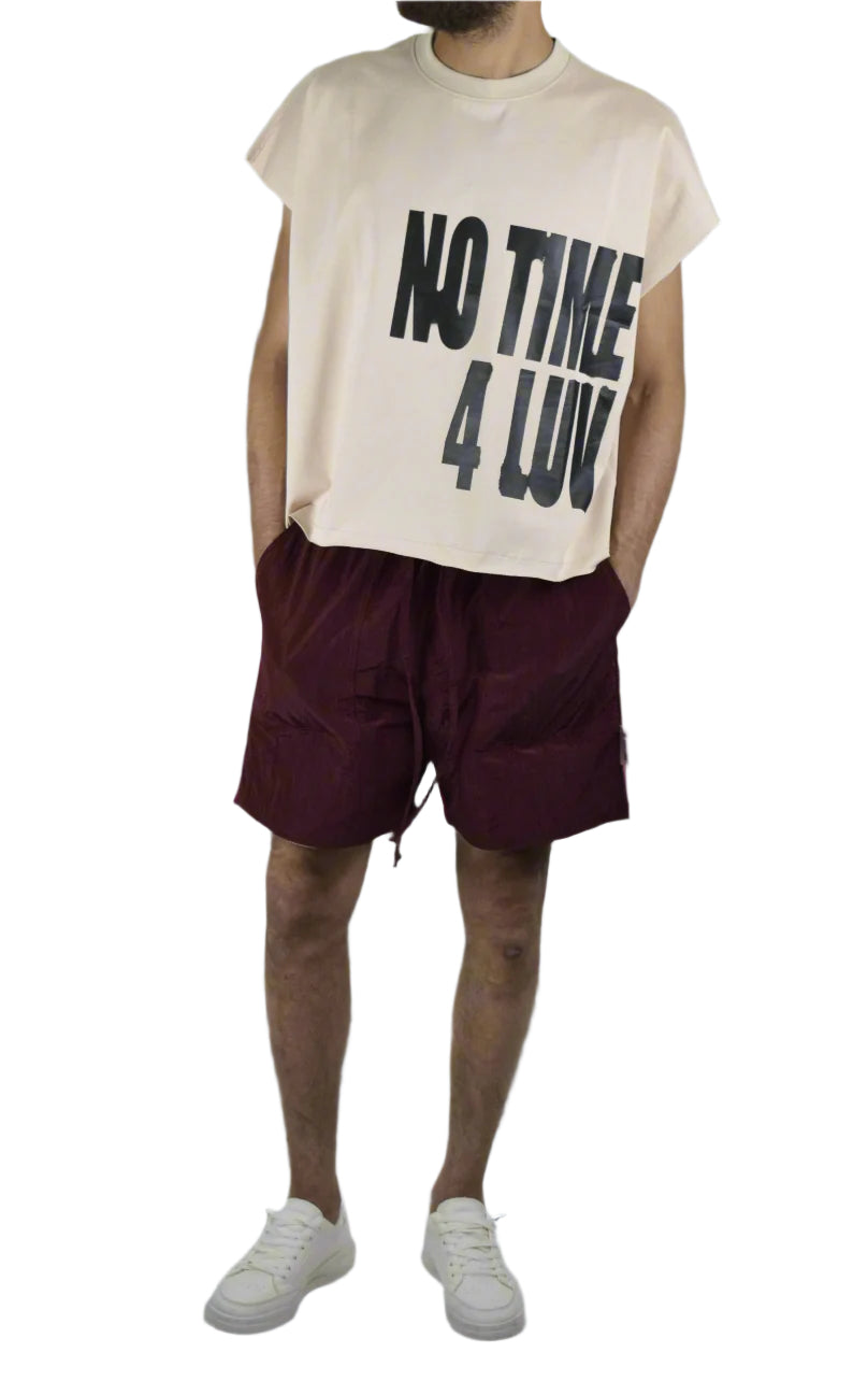 Person wearing a beige t-shirt with text and maroon shorts on a gray background