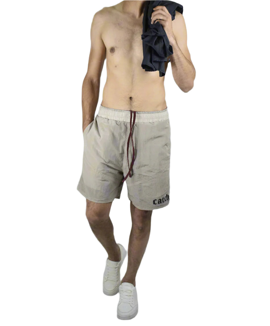 Man wearing beige shorts and white sneakers on a plain background